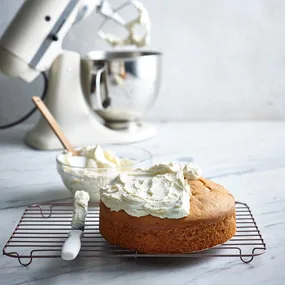 Butter cake with icing on top and a standmixer in background