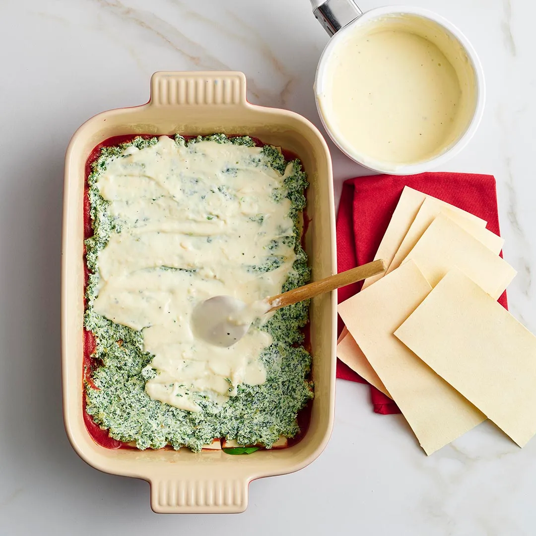 adding bechamel sauce to the spinach and ricotta lasagne