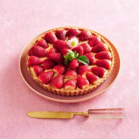 strawberry tart on a plate with a serving knife in front