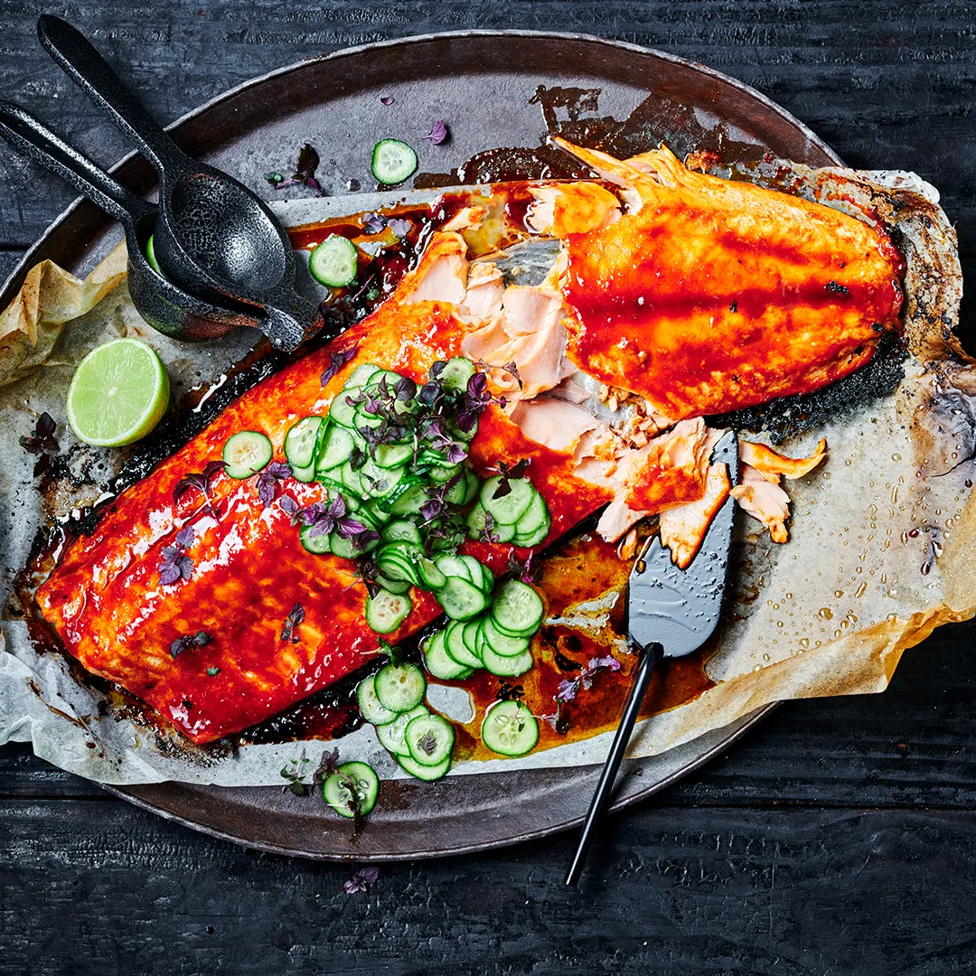 Barbecued side of salmon with a quick pickled cucumber on a platter