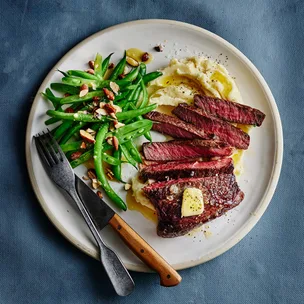 Chargrilled rump steak with Dijon maple butter, green beans and mashed potato on a dinner plate