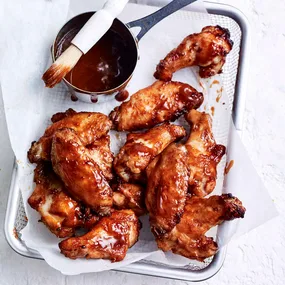 air fryer chicken nibbles in a basket with glaze in a small pot