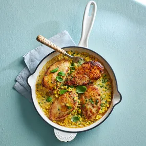 chicken dinner recipe of four chicken breasts on a creamy corn sauce in a pan