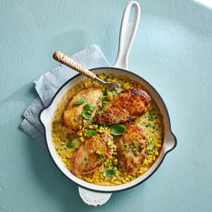 chicken dinner recipe of four chicken breasts on a creamy corn sauce in a pan