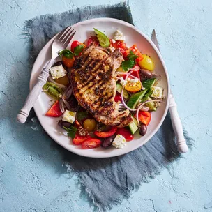 pork chop on a Greek salad in a bowl