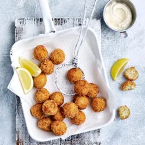 air fryer arancini on a serving dish with wedges of lemon