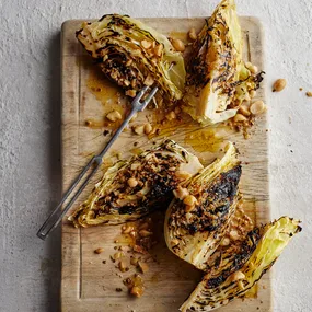 Slices of barbecued sugarloaf cabbage with bush tomato butter on a board