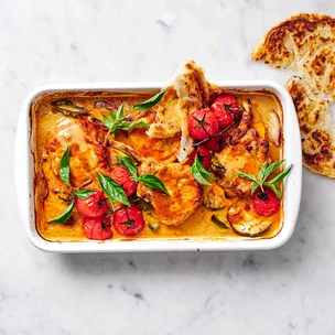 four pork cutlets in a baking dish with a red curry sauce