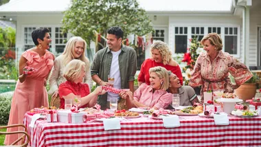 The cast of Christmas with The Australian Women's Weekly celebrate a festive feast on a long table