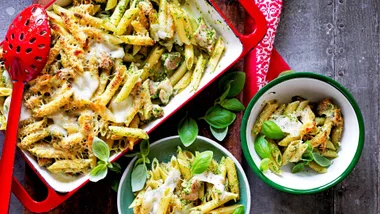 Chicken and pesto pasta bake in a baking dish with serving bowls - one of our pasta bake recipes