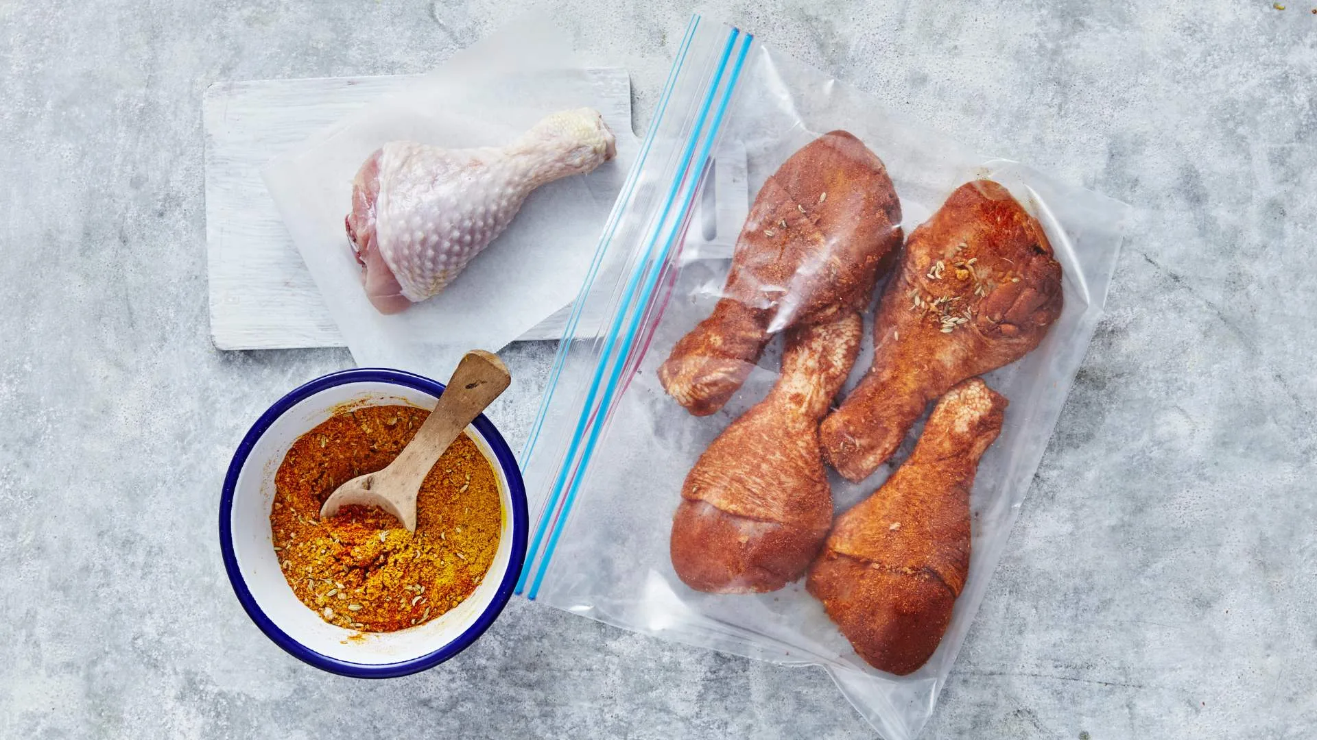 Marinating chicken drumsticks in a plastic bag, with a bowl of spice rub, for chicken wings and drumsticks recipes