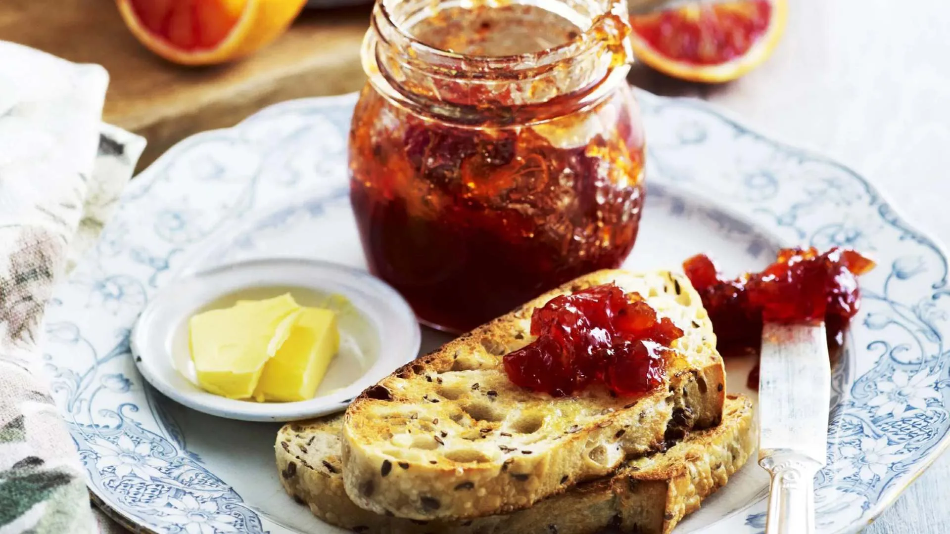 How to sterilise jars - an image of bitter blood orange and Campari marmalade jam in a jar, with a slice of toast on a plate, butter and knife