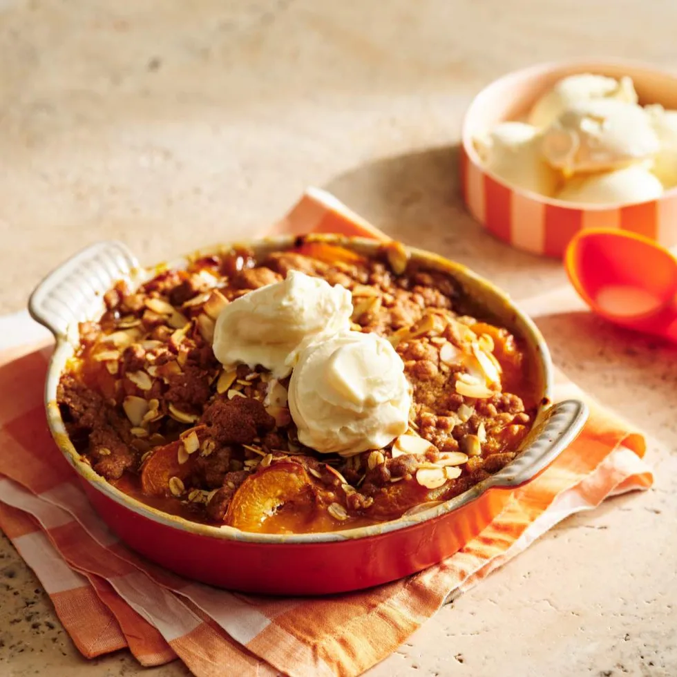 Apricot crumble in a baking dish served with vanilla ice-cream