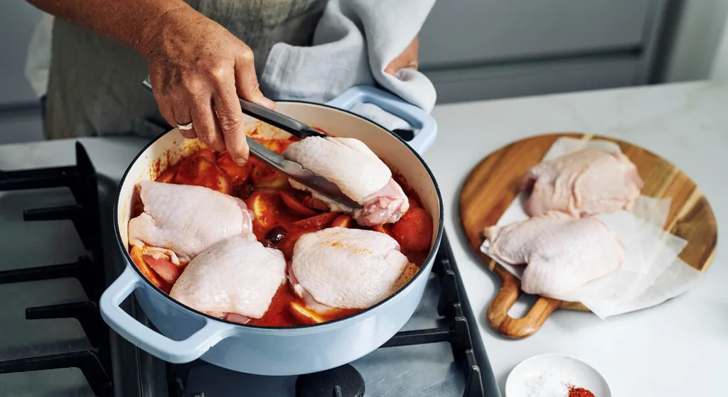 Julie Goodwin’s Spanish chicken tray bake cooking step, chicken thigh cutlets being placed into casserole dish