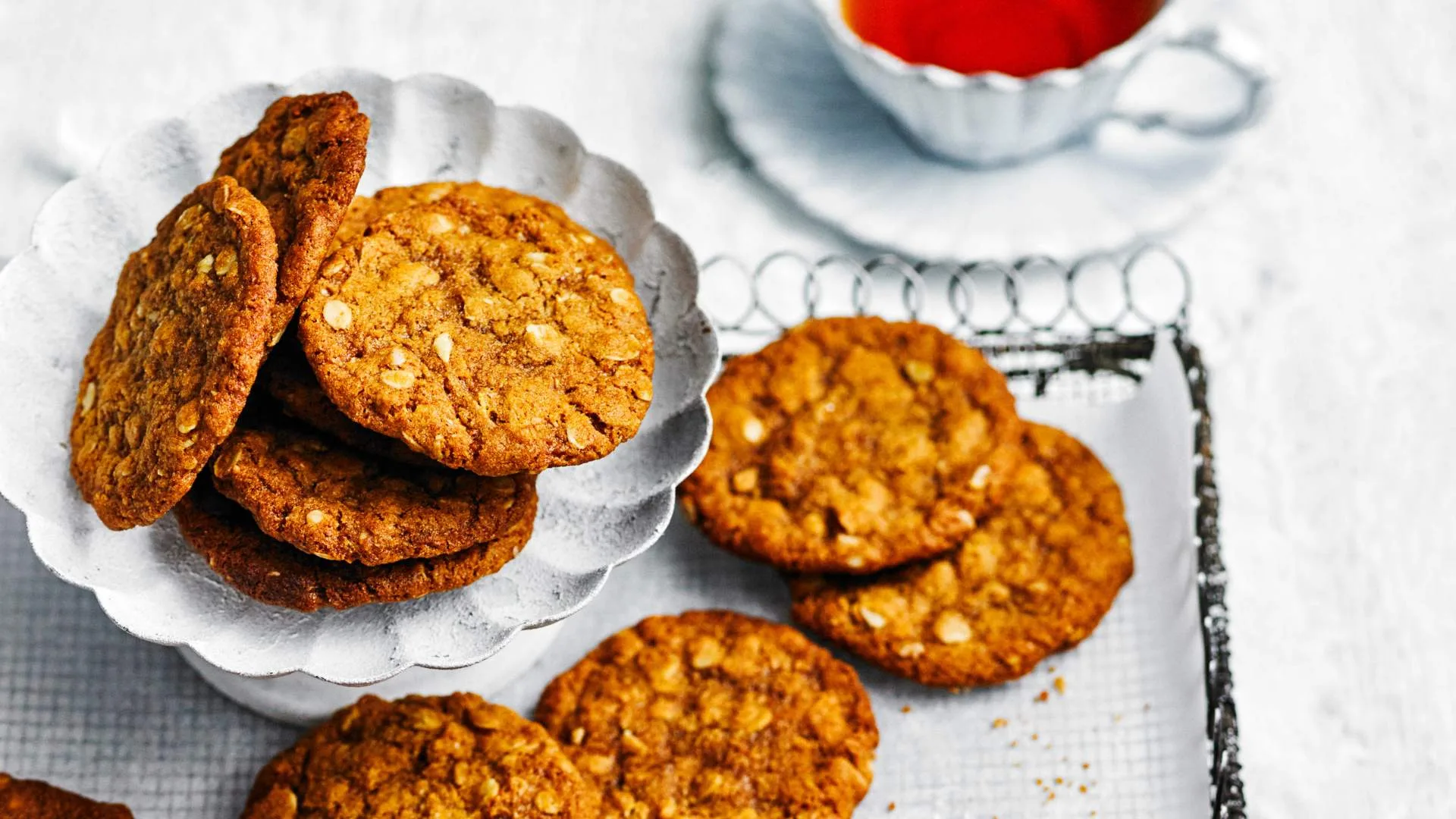 Anzac biscuits on a tray with a cup of tea