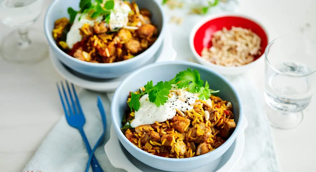 Julie Goodwin’s one pan chicken pilaf served in bowls, topped with yoghurt and fresh coriander.