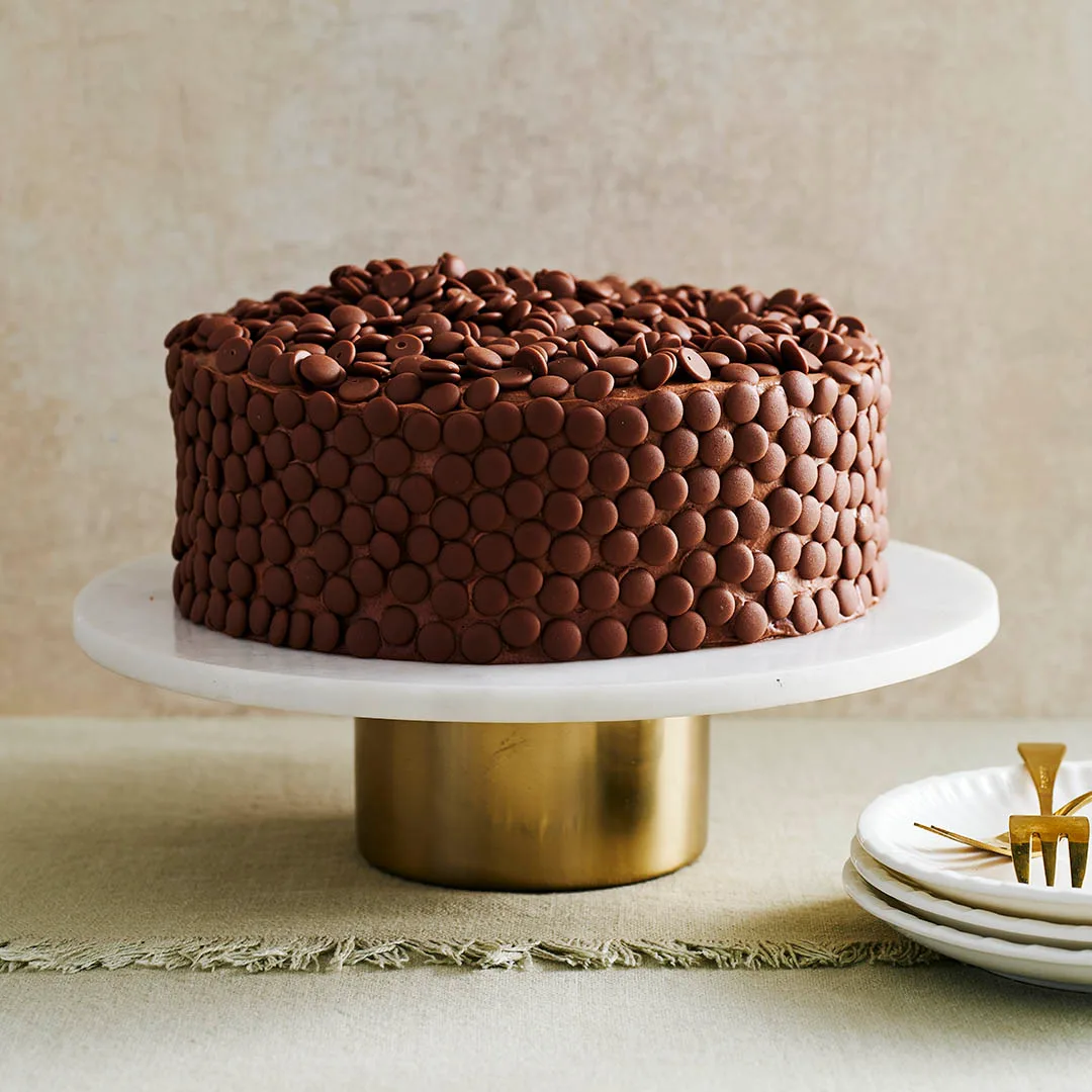 Moist chocolate cake on a stand decorated with choc melts