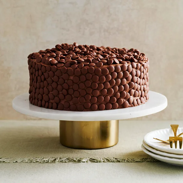 Moist chocolate cake on a stand decorated with choc melts