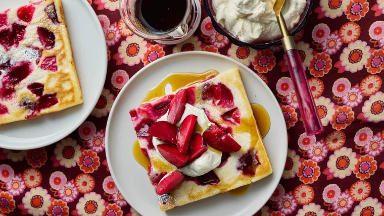 Sheet pan pancakes served with extra plums, ricotta, plum wedges and maple syrup.