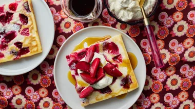 Sheet pan pancakes served with extra plums, ricotta, plum wedges and maple syrup.