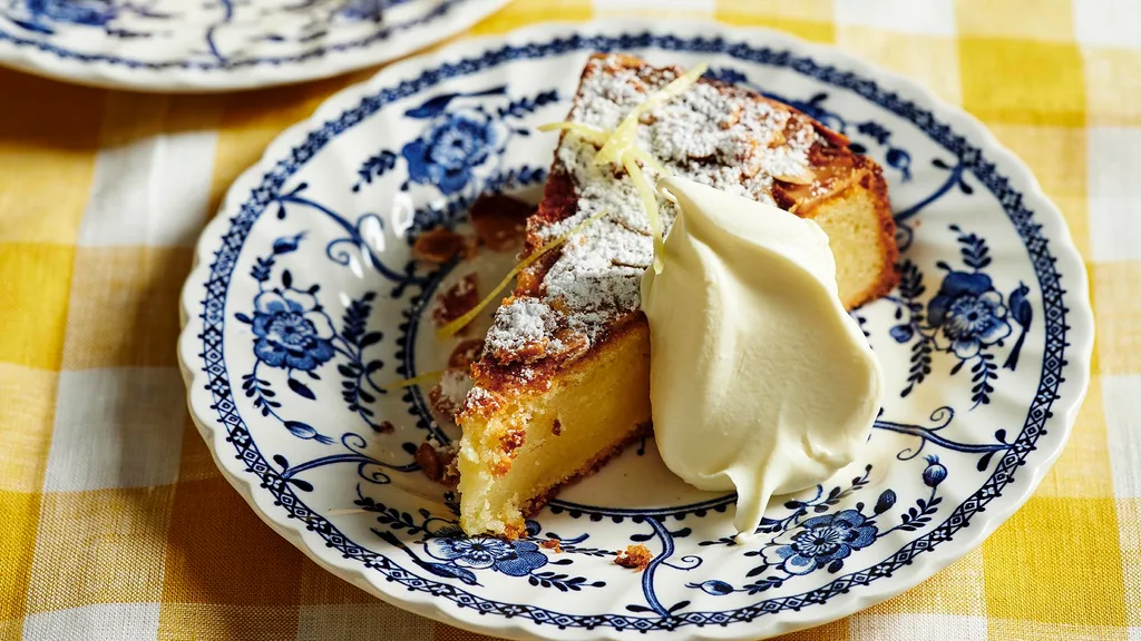 A slice of lemon ricotta cake with cream on a blue and white plate