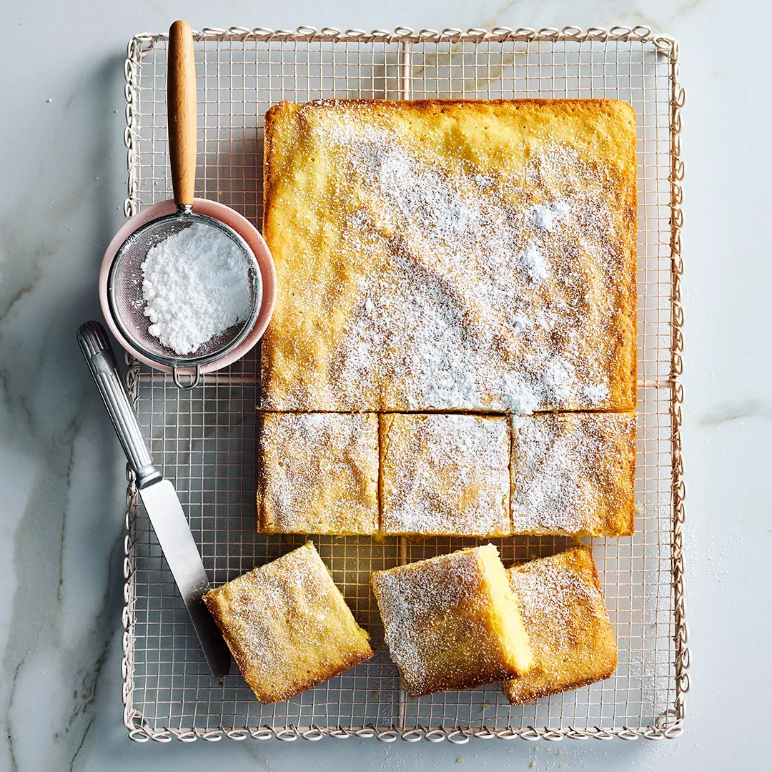 Julie Goodwin's lemon coconut slice on a wire cooling rack, half cut into slices
