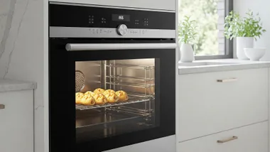 Stainless steel smart oven in a light and airy kitchen, with baked goods visible through the open door.