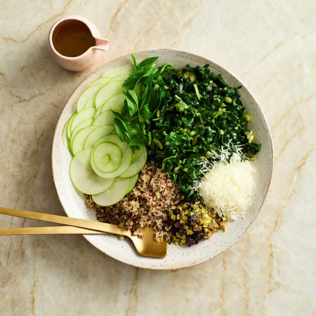 Easy apple slaw in a serving bowl with lemon honey dressing in a jug.
