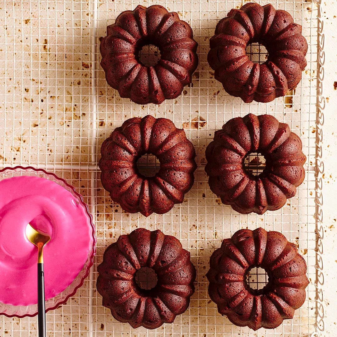 Un-iced beetroot chocolate bundt cakes with a bowl of icing on the side