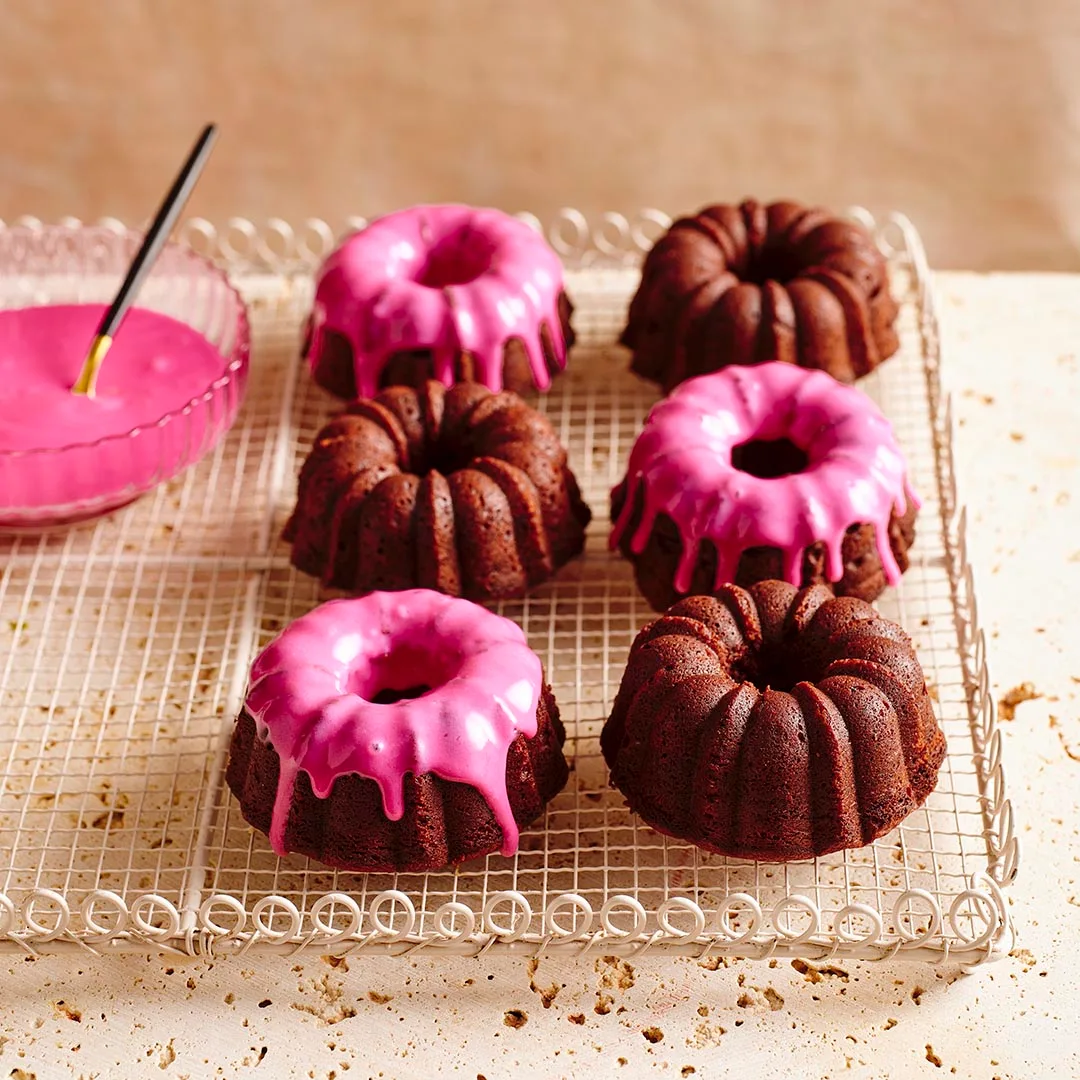 Mini beetroot chocolate bundt cakes, some iced and some not, on a cake rack.