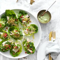poached chicken salad in lettuce leaves with a green tahini dressing in a bowl
