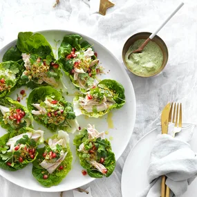 poached chicken salad in lettuce leaves with a green tahini dressing in a bowl
