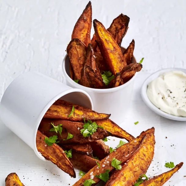 air fryer sweet potato fries in cups with sour cream in a bowl on the side