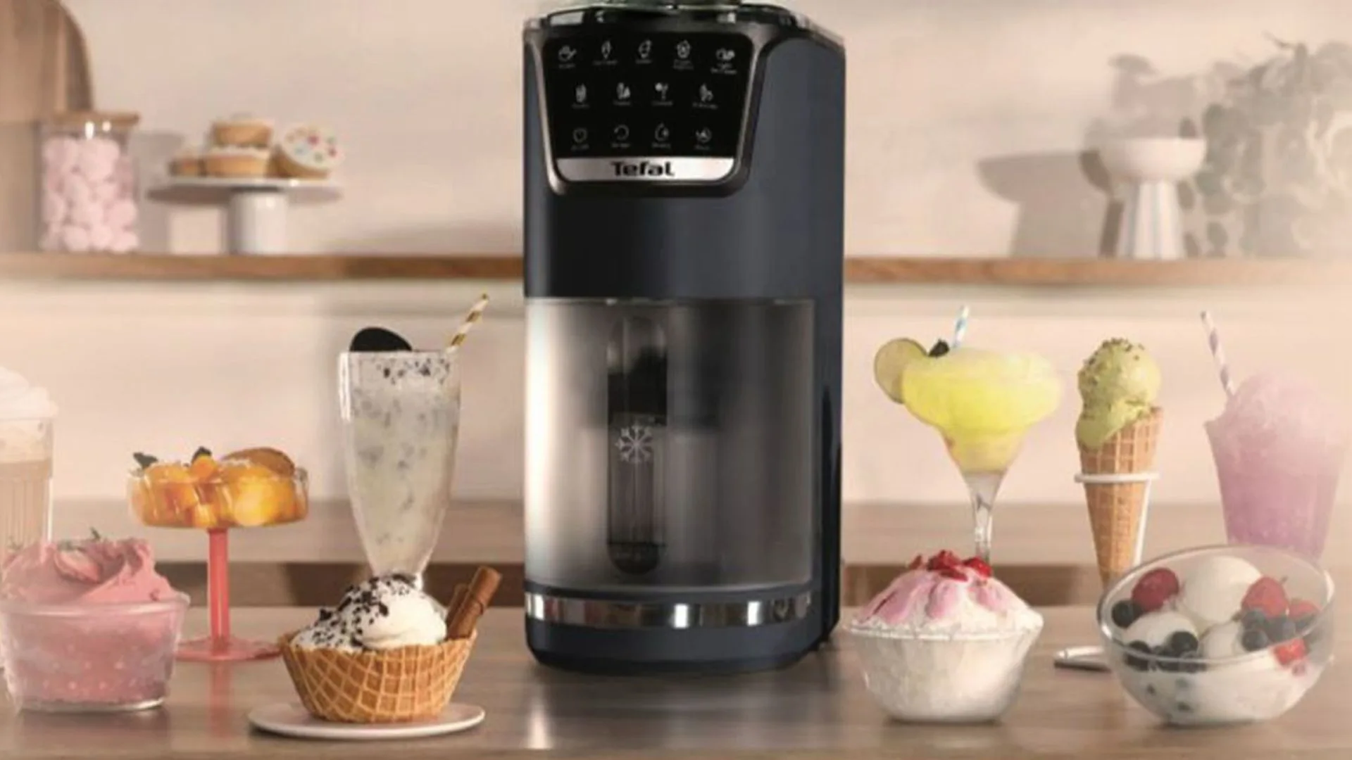 A black Tefal Dolci ice cream maker on a counter surrounded by various frozen treats, including milkshakes, sorbets, ice cream in a waffle cone, and servings topped with fruit.