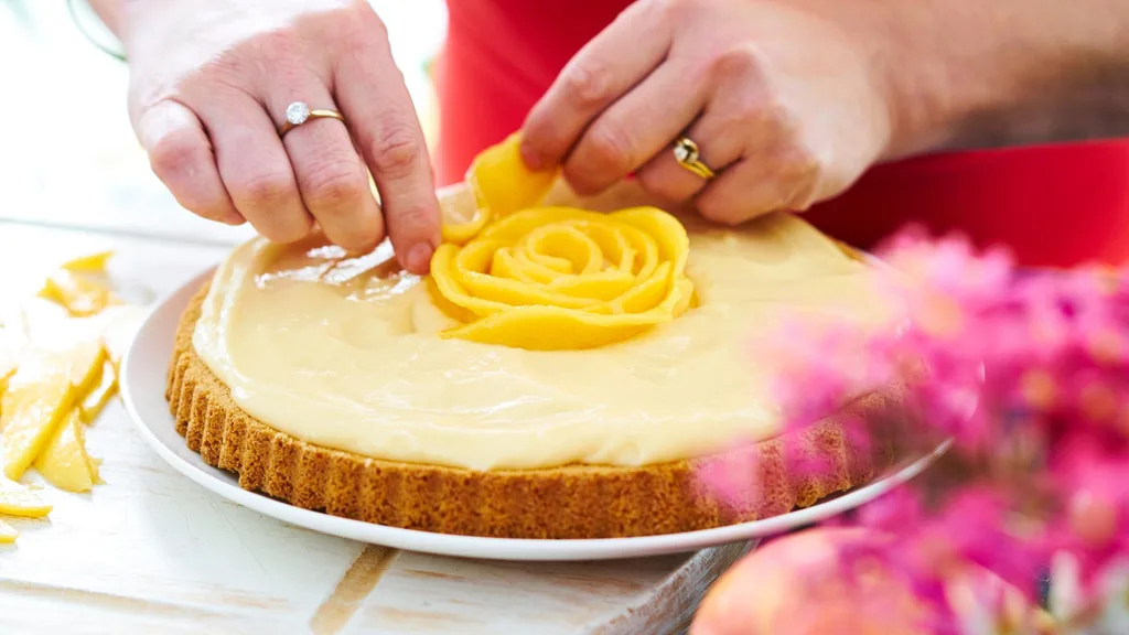 Arranging mango slices in a rose pattern on this cake
