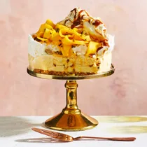 Frozen mango pavlova with passionfruit on a gold cake stand