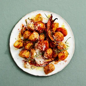 Roast baby potatoes with chilli on a white plate on top of a green cloth