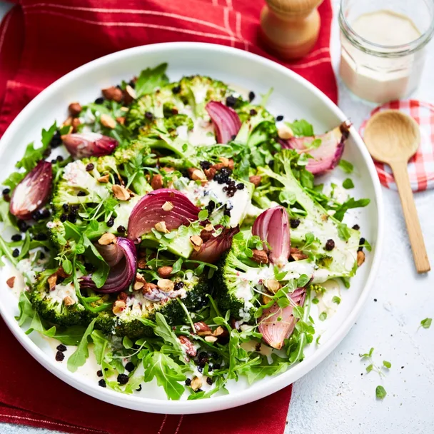 Roasted broccoli salad with creamy chilli dressing on a white serving platter over a red cloth