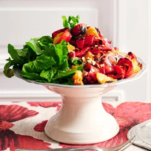 Capsicum salad with sherry vinegar dressing on a platter with rocket leaves