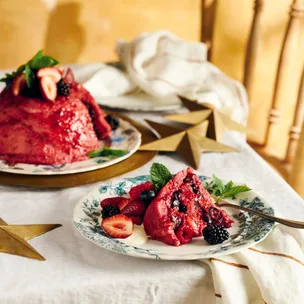 Maggie Beer's summer pudding, plus a slice of the pudding, on blue and white plates on a table.