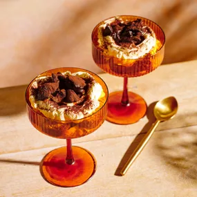 Maggie Beer's tiramisu with prunes and vino cotto recipe in two red serving glasses with a golden spoon