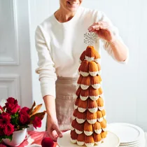 A woman placing a star decoration at the top of a madeleine tower