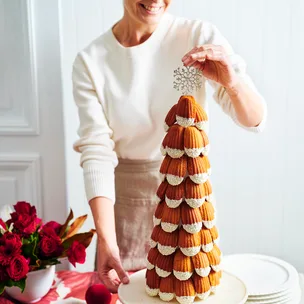 A woman placing a star decoration at the top of a madeleine tower