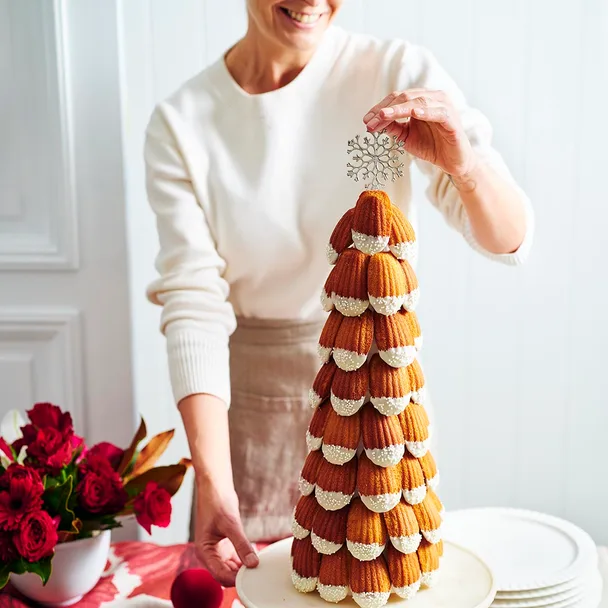 A woman placing a star decoration at the top of a madeleine tower