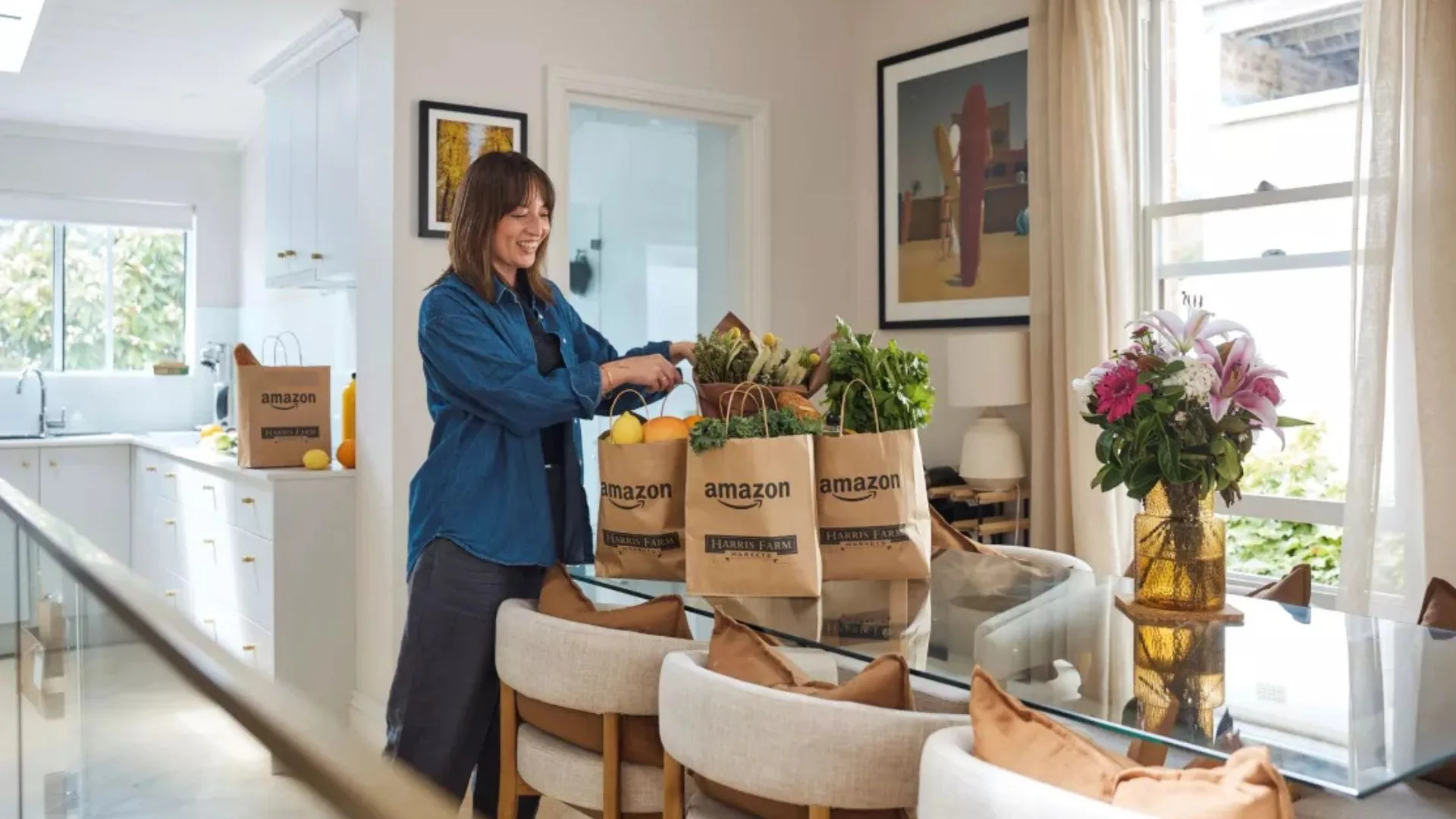 A woman in a bright kitchen unpacking fresh produce from Amazon and Harris Farm Markets grocery bags - Harris Farm Amazon
