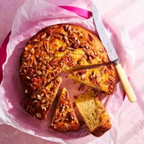 Easy banana cake made from cake topped with pecans on a pink plate.