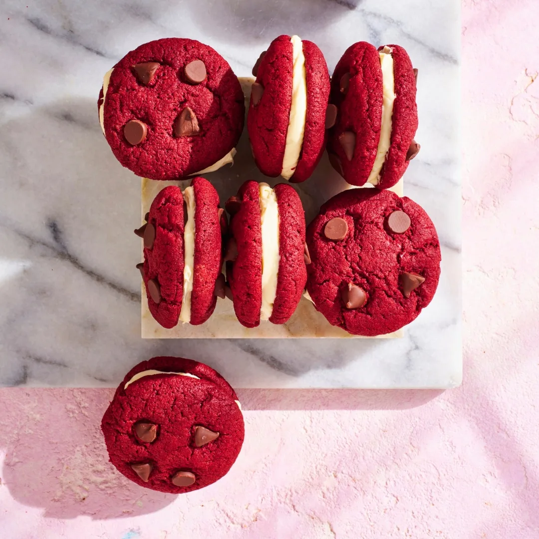 red velvet cookies sandwiched with icing on a marble slab