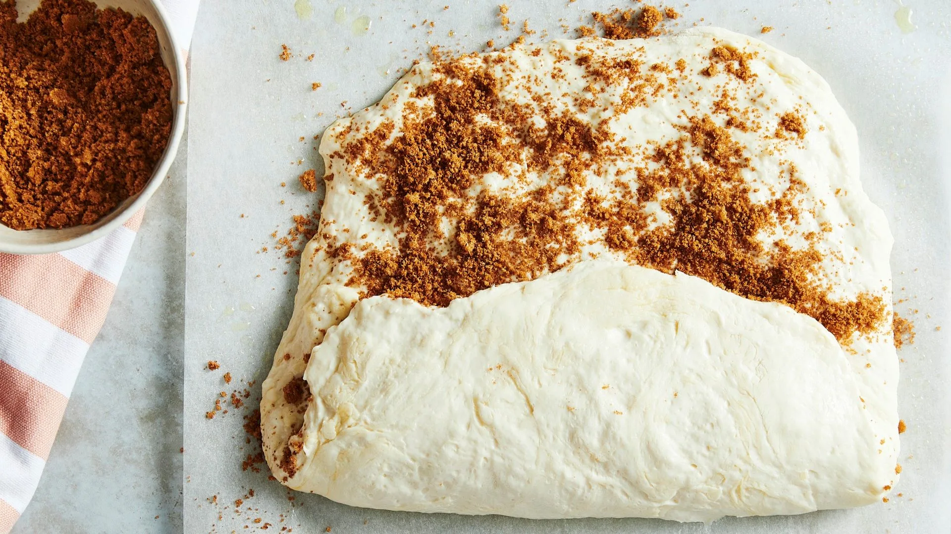 cinnamon focaccia dough half rolled on a sheet of baking paper