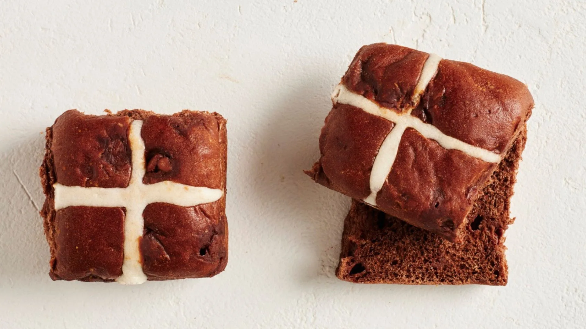 two chocolate hot cross buns, one cut in half