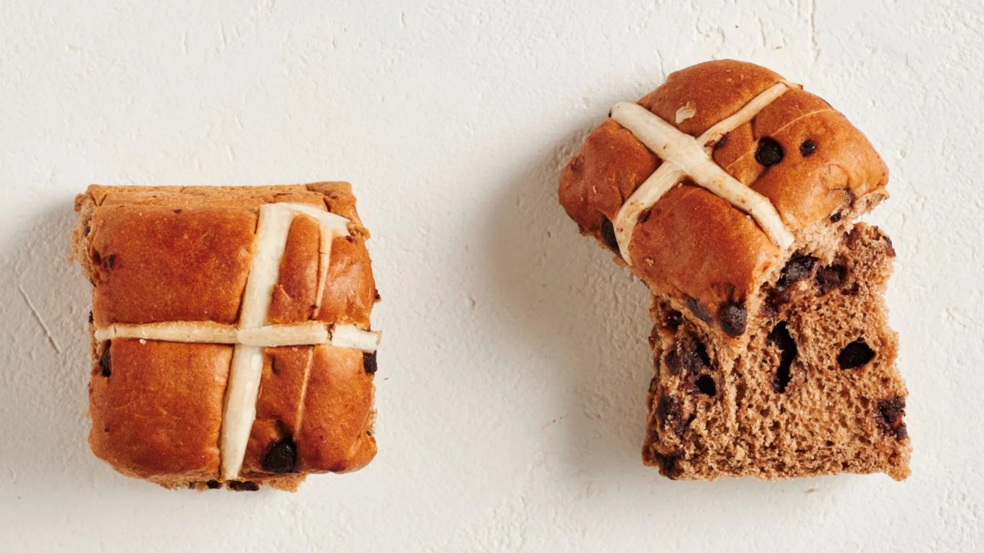 two chocolate hot cross buns, one cut in half